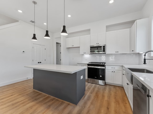 kitchen featuring backsplash, stainless steel appliances, pendant lighting, white cabinets, and a kitchen island