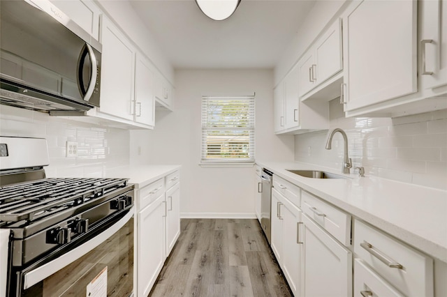 kitchen with light hardwood / wood-style flooring, stainless steel appliances, white cabinetry, and sink