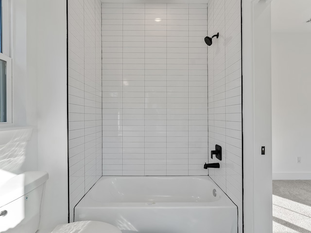 bathroom featuring tiled shower / bath combo and toilet