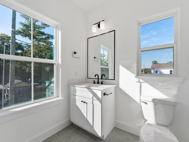 bathroom with tile patterned flooring, vanity, a healthy amount of sunlight, and toilet