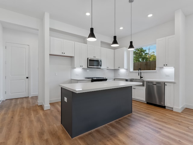 kitchen featuring white cabinetry, a center island, stainless steel appliances, decorative light fixtures, and decorative backsplash