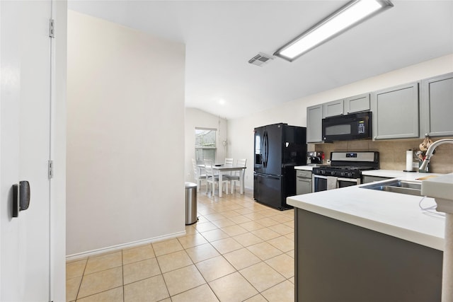 kitchen featuring gray cabinetry, sink, black appliances, lofted ceiling, and light tile patterned flooring