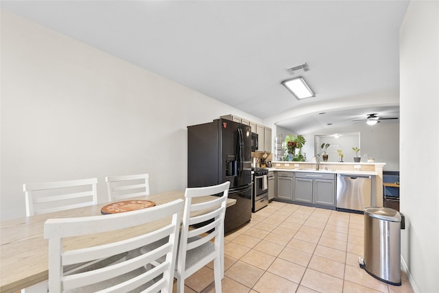 kitchen featuring lofted ceiling, ceiling fan, gray cabinets, light tile patterned floors, and appliances with stainless steel finishes