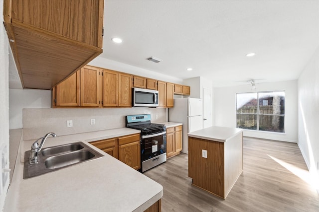 kitchen featuring ceiling fan, sink, stainless steel appliances, a kitchen island, and light wood-type flooring