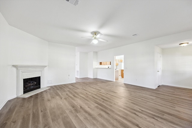 unfurnished living room with hardwood / wood-style floors, ceiling fan, and a premium fireplace