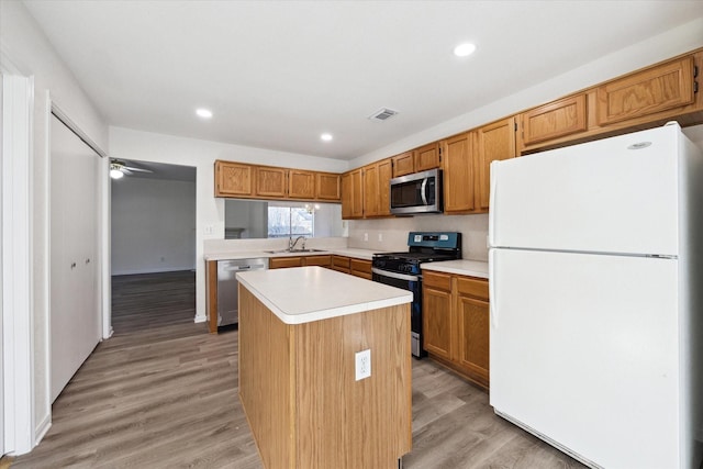 kitchen featuring ceiling fan, sink, a center island, stainless steel appliances, and light hardwood / wood-style flooring