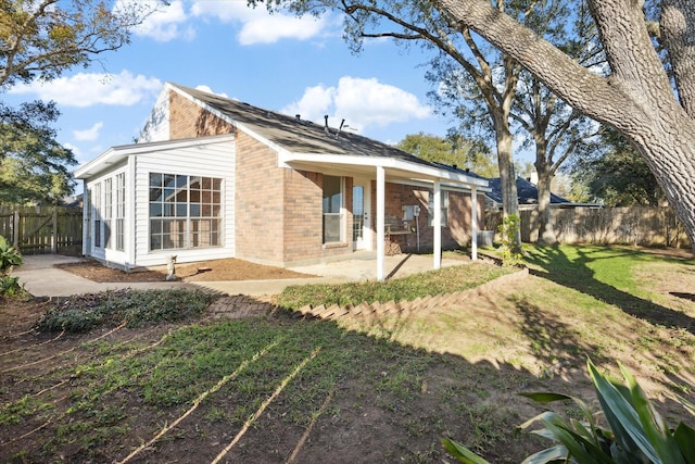 rear view of property with a lawn and a patio