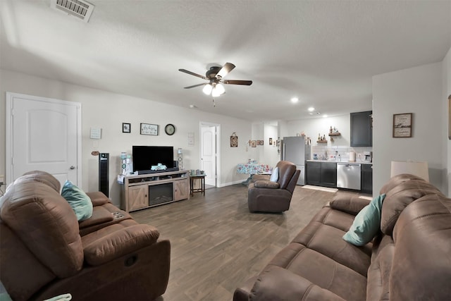 living room with ceiling fan, wood-type flooring, a textured ceiling, and bar