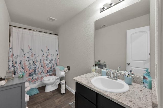 full bathroom with shower / bath combo, a textured ceiling, toilet, vanity, and hardwood / wood-style flooring