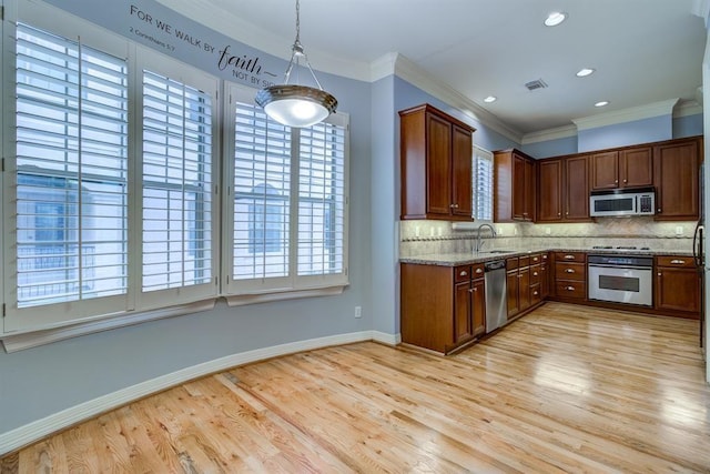 kitchen featuring sink, light stone countertops, decorative light fixtures, light hardwood / wood-style floors, and stainless steel appliances