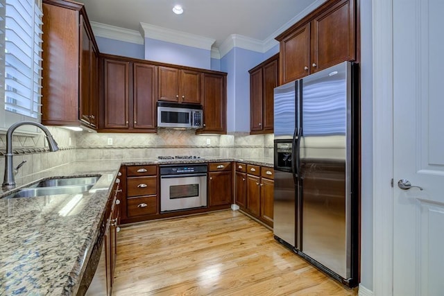 kitchen with light stone countertops, sink, crown molding, and appliances with stainless steel finishes