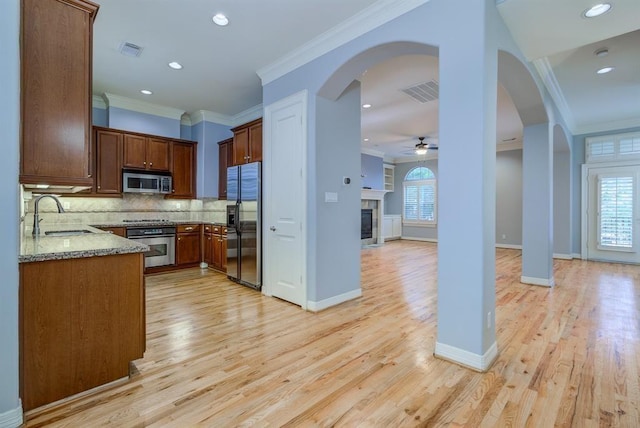 kitchen featuring sink, decorative backsplash, ornamental molding, light stone counters, and stainless steel appliances