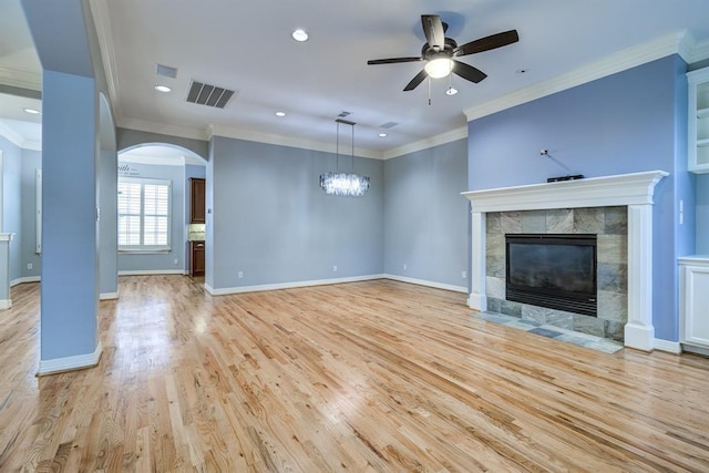 unfurnished living room featuring a fireplace, ornamental molding, ceiling fan with notable chandelier, and light hardwood / wood-style flooring