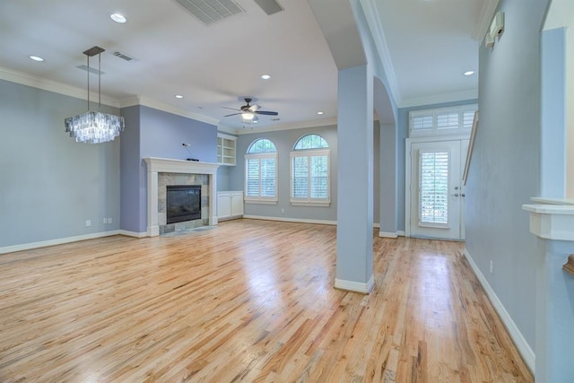 unfurnished living room featuring a tile fireplace, ceiling fan with notable chandelier, light hardwood / wood-style flooring, and ornamental molding