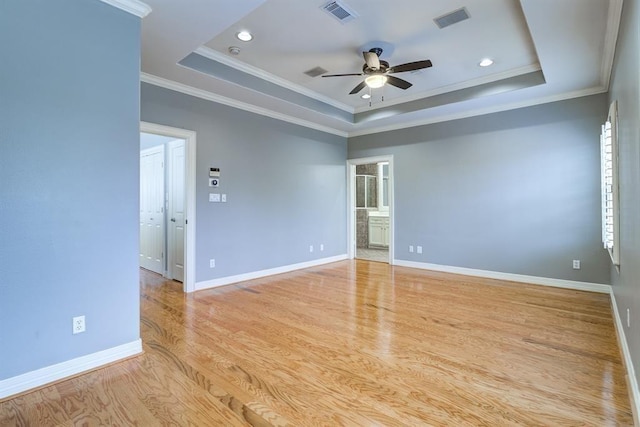 spare room featuring a tray ceiling, ceiling fan, light hardwood / wood-style floors, and ornamental molding