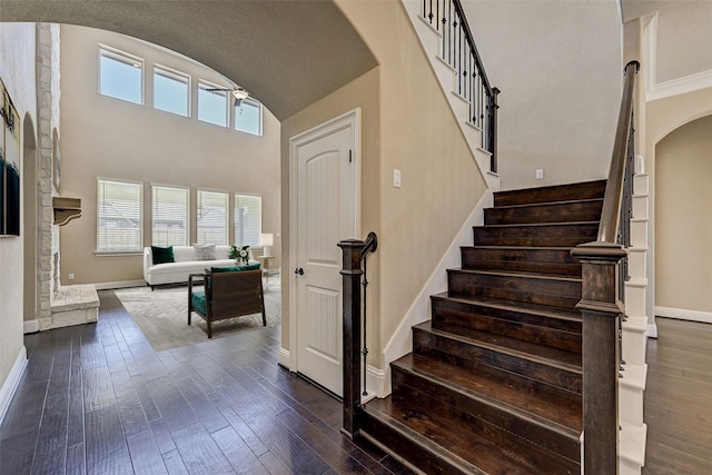 stairs with a fireplace, wood-type flooring, ceiling fan, and crown molding