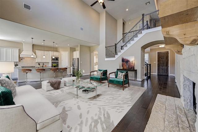 living room with a fireplace, sink, dark hardwood / wood-style floors, and a high ceiling