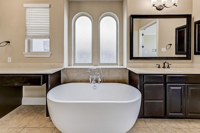 bathroom with tile patterned floors, a tub, vanity, and a healthy amount of sunlight