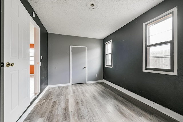 unfurnished bedroom with light hardwood / wood-style floors and a textured ceiling