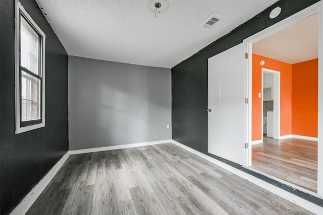 spare room featuring light wood-type flooring and a textured ceiling