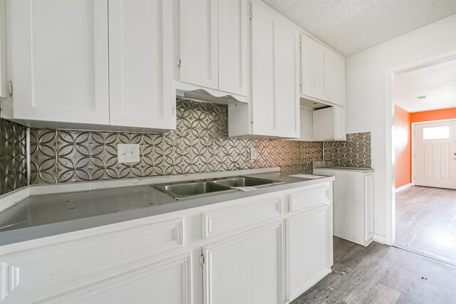 kitchen featuring backsplash, white cabinets, a textured ceiling, and hardwood / wood-style flooring