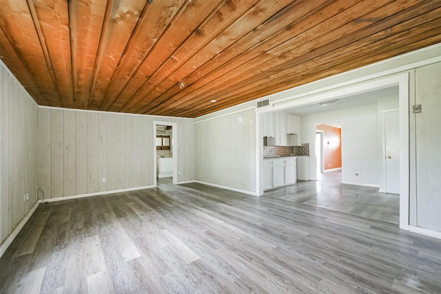 unfurnished living room with hardwood / wood-style flooring, wood ceiling, and wooden walls