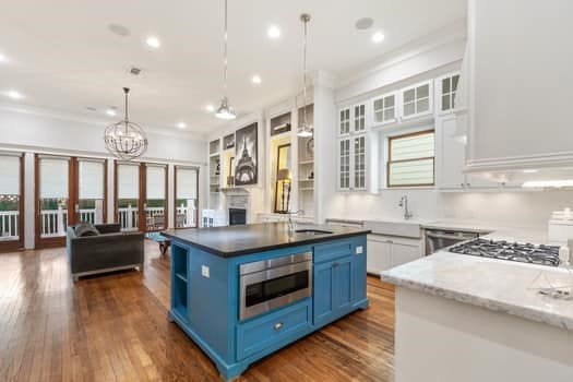 1148 Nicholson St, Houston, TX 77008 - kitchen featuring open floor plan, an island with sink, stainless steel microwave, blue cabinets, and dark wood finished floors