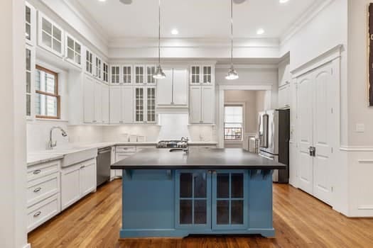 1148 Nicholson St, Houston, TX 77008 - kitchen with crown molding, white cabinets, a center island with sink, and stainless steel appliances
