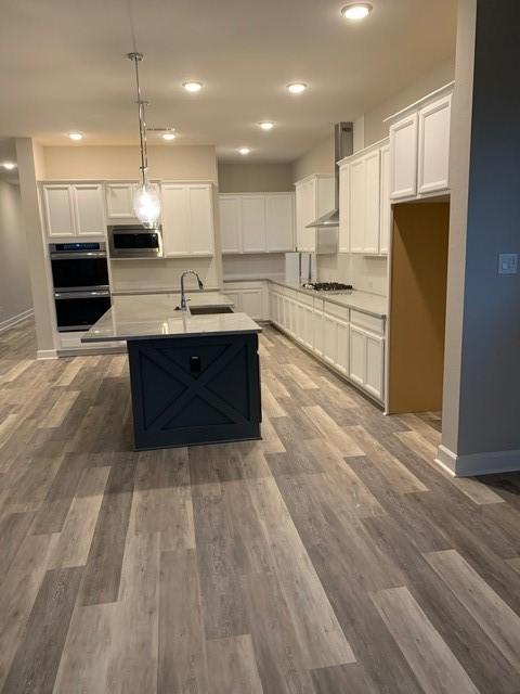 kitchen with stainless steel appliances, decorative light fixtures, and white cabinetry