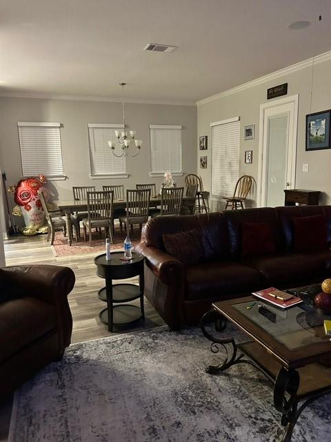 living room featuring an inviting chandelier, crown molding, and wood-type flooring