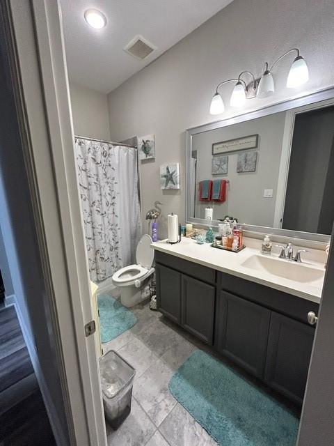 bathroom featuring a shower with shower curtain, vanity, and toilet