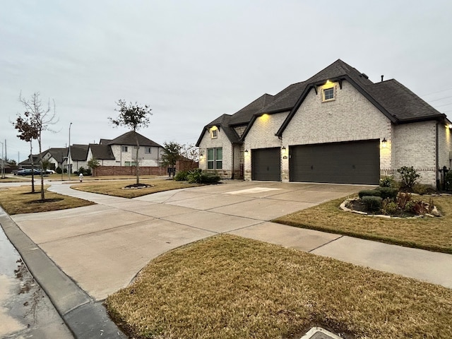 french provincial home featuring a front yard and a garage