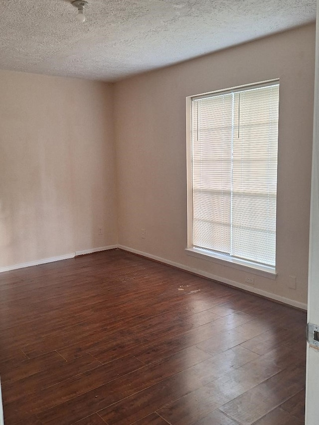 spare room with a textured ceiling and dark hardwood / wood-style flooring