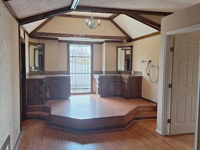 interior space featuring hardwood / wood-style floors, vaulted ceiling with beams, a textured ceiling, and a notable chandelier