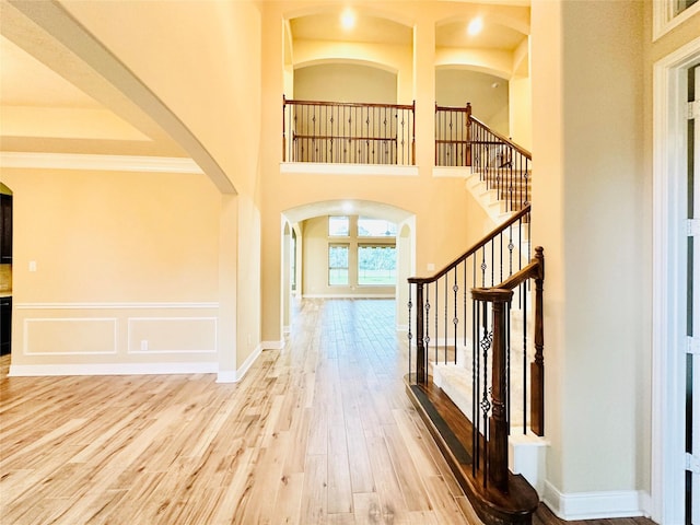 foyer with hardwood / wood-style floors, ornamental molding, and a high ceiling