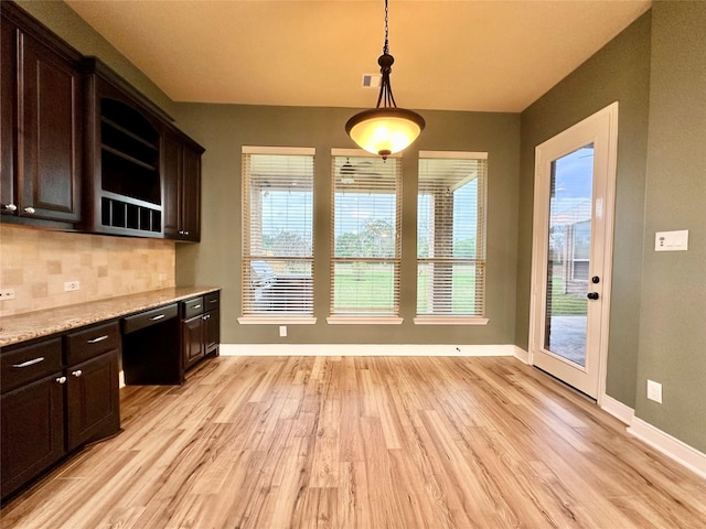 kitchen featuring backsplash, dark brown cabinetry, and pendant lighting