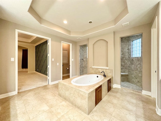 bathroom with a raised ceiling and shower with separate bathtub