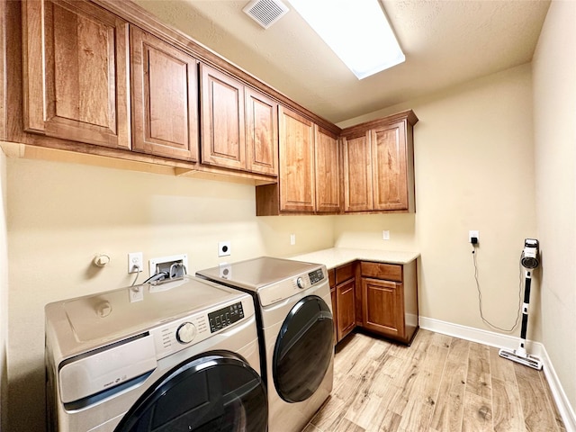 washroom with separate washer and dryer, cabinets, and light hardwood / wood-style floors