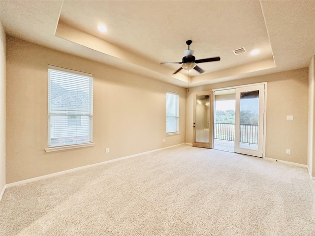 carpeted spare room with ceiling fan, a raised ceiling, and french doors