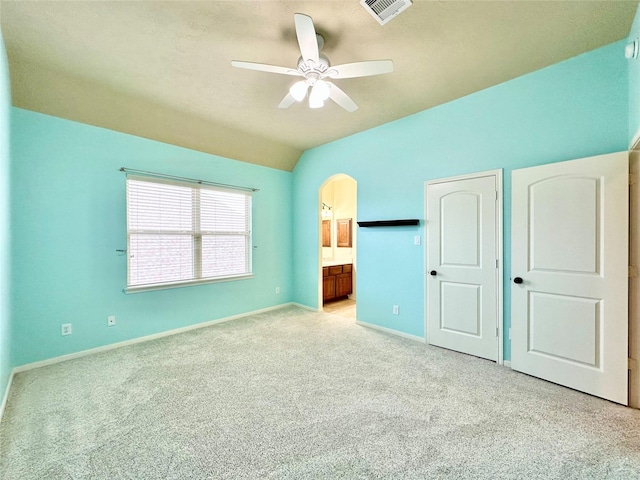 unfurnished bedroom featuring ceiling fan, lofted ceiling, light carpet, and connected bathroom