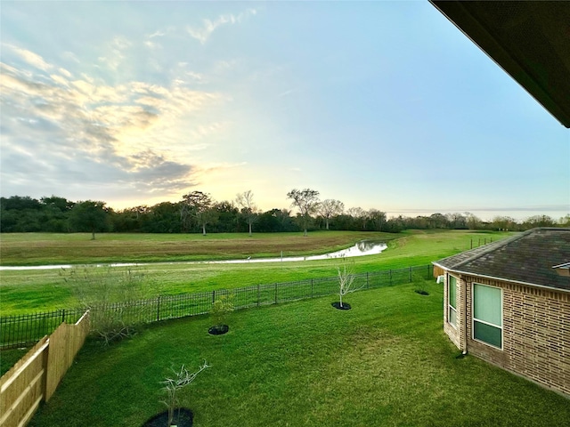 yard at dusk with a rural view and a water view