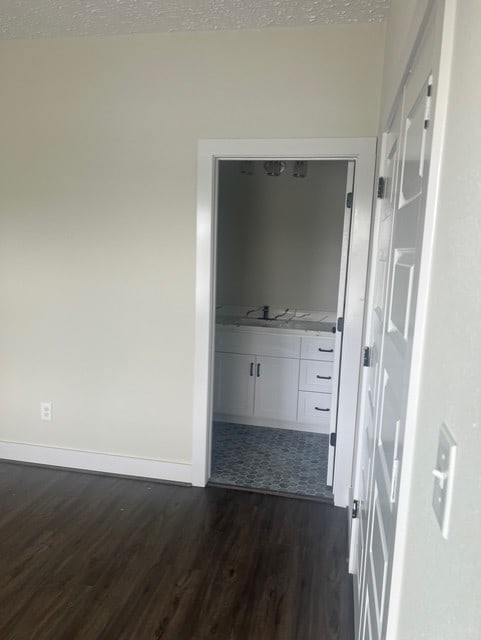hall with dark wood-type flooring, a textured ceiling, and baseboards