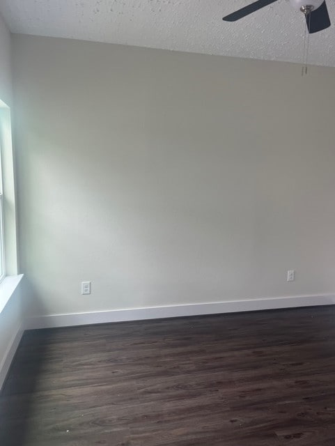 empty room featuring baseboards, a textured ceiling, ceiling fan, and dark wood-style floors