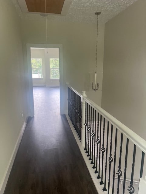 hall with baseboards, attic access, wood finished floors, and an upstairs landing