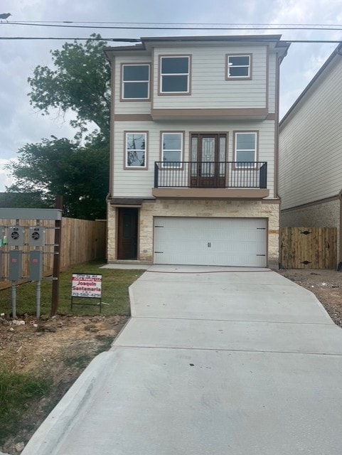 view of front of property featuring a garage, fence, driveway, and stone siding