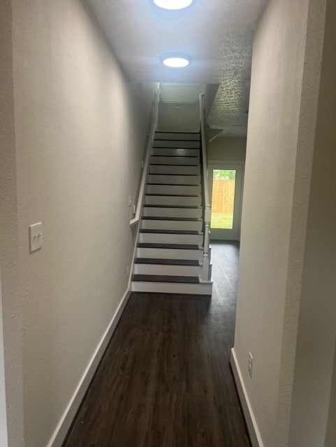 hallway with stairway, baseboards, and wood finished floors