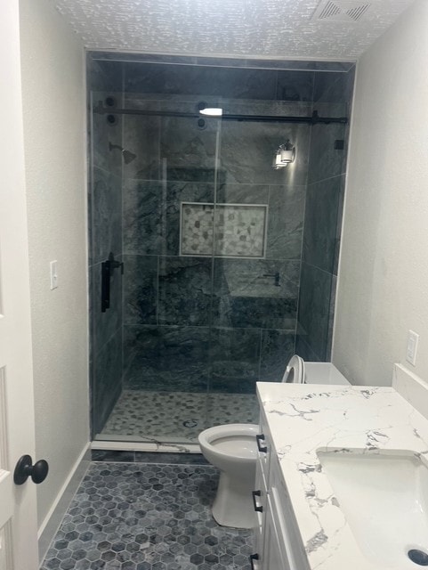 bathroom with vanity, a stall shower, toilet, and a textured ceiling