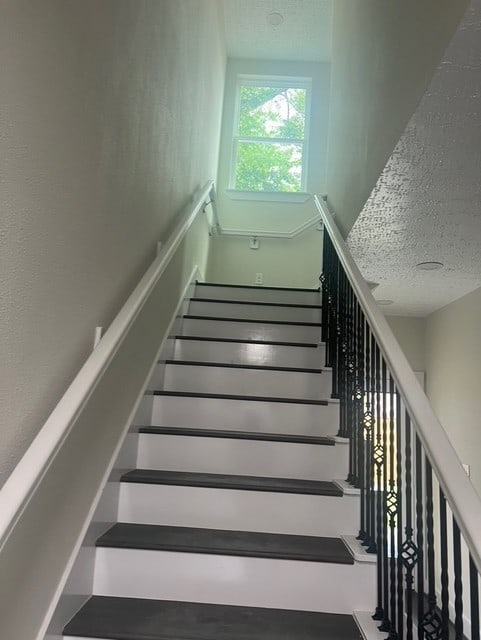 stairway featuring a textured ceiling