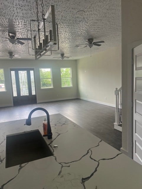unfurnished living room with a ceiling fan and baseboards