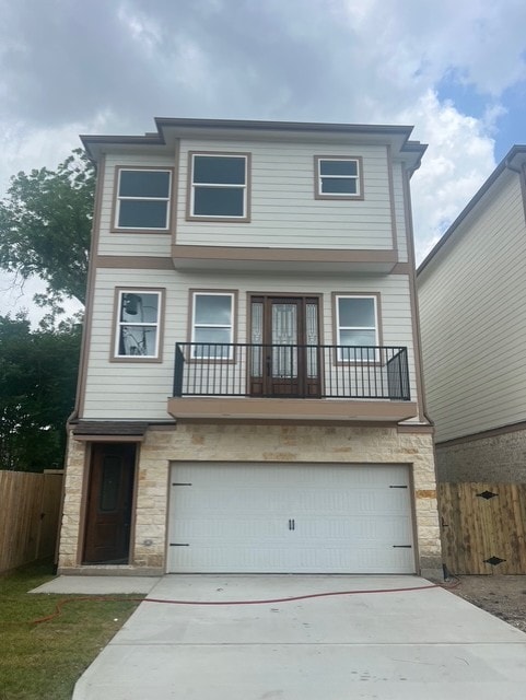 view of front facade with concrete driveway, fence, stone siding, and a garage